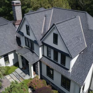 aerial-view-large-elegant-home-surrounded-by-lush-greenery-showcasing-its-beautiful-architecture-dark-shingled-roof